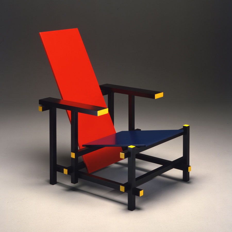 Chair built from geometric pieces of wood lacquered in yellow, black, blue, and red.
