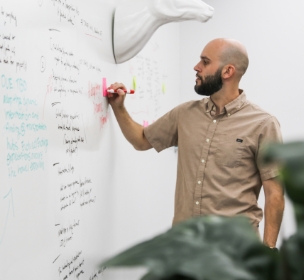 a photo of an Adcetera employee taking notes on a whiteboard during a meeting