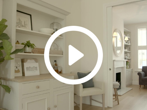 Sophisticated home interior with wooden floors featuring white shelving unit with trinkets next to white padded chair  Microsoft Teams background