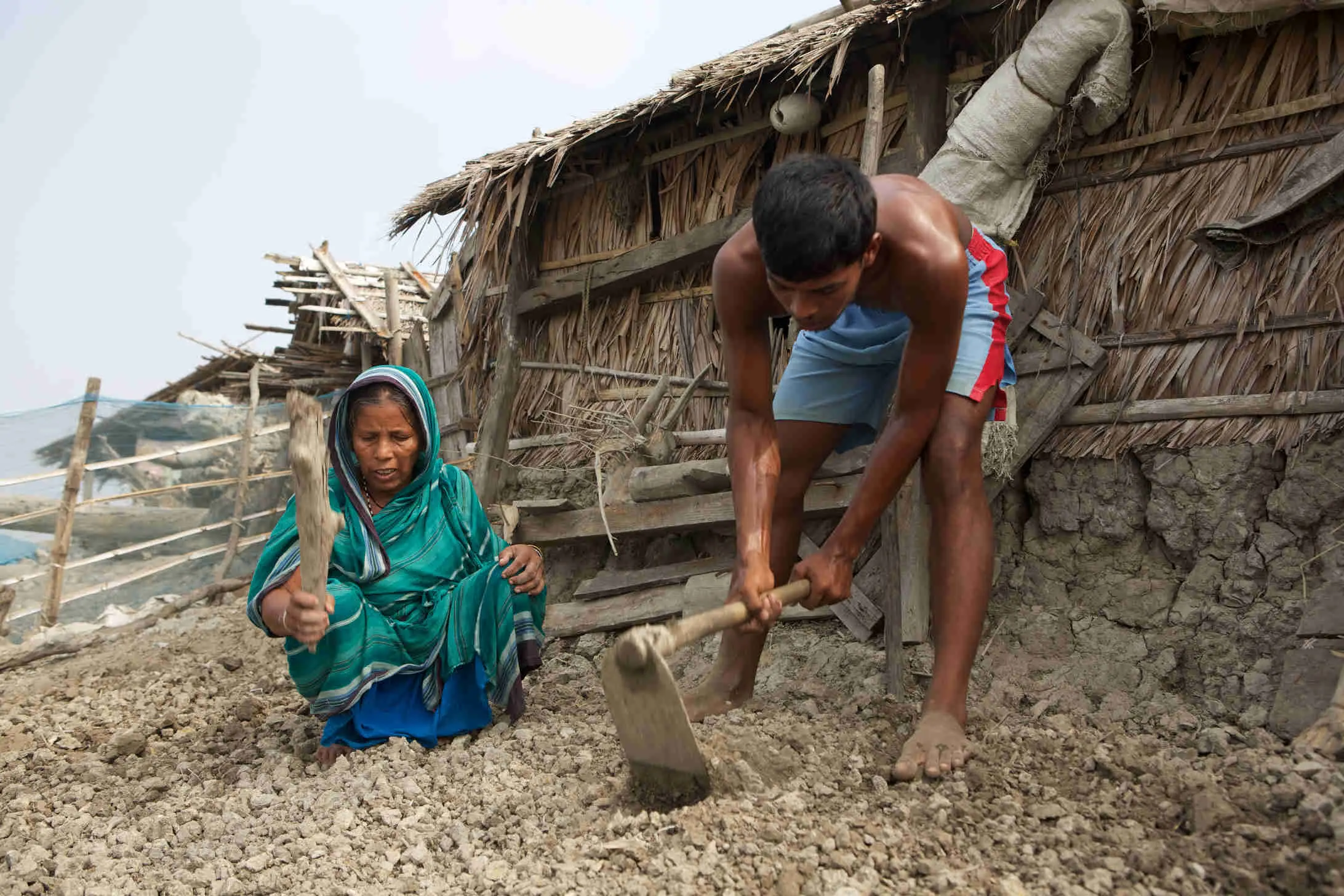 Bangladeshi woman and grandchild preparing a patch to grow vegetables