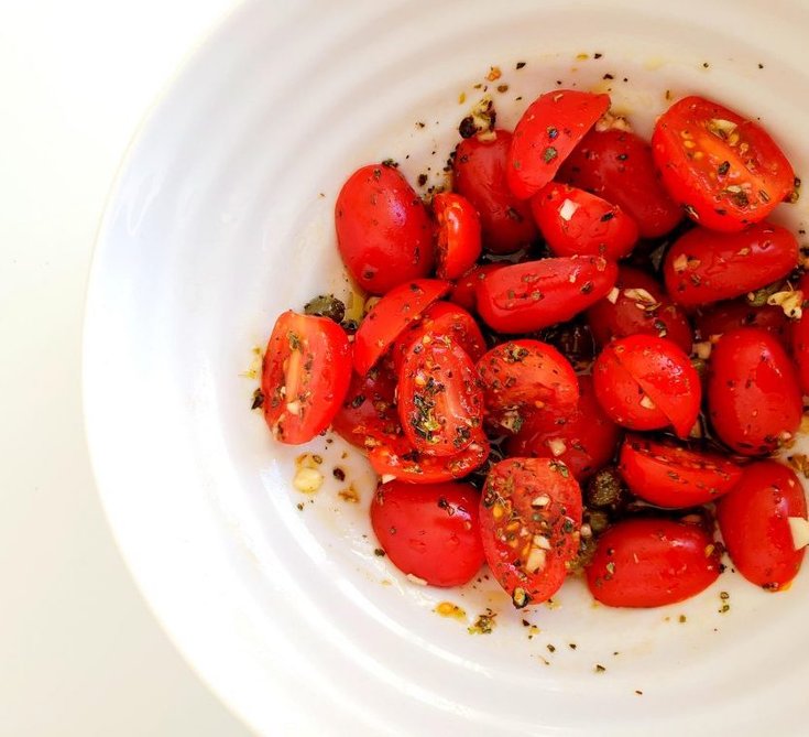 Bowl of cherry tomatoes marinating in Italian spices