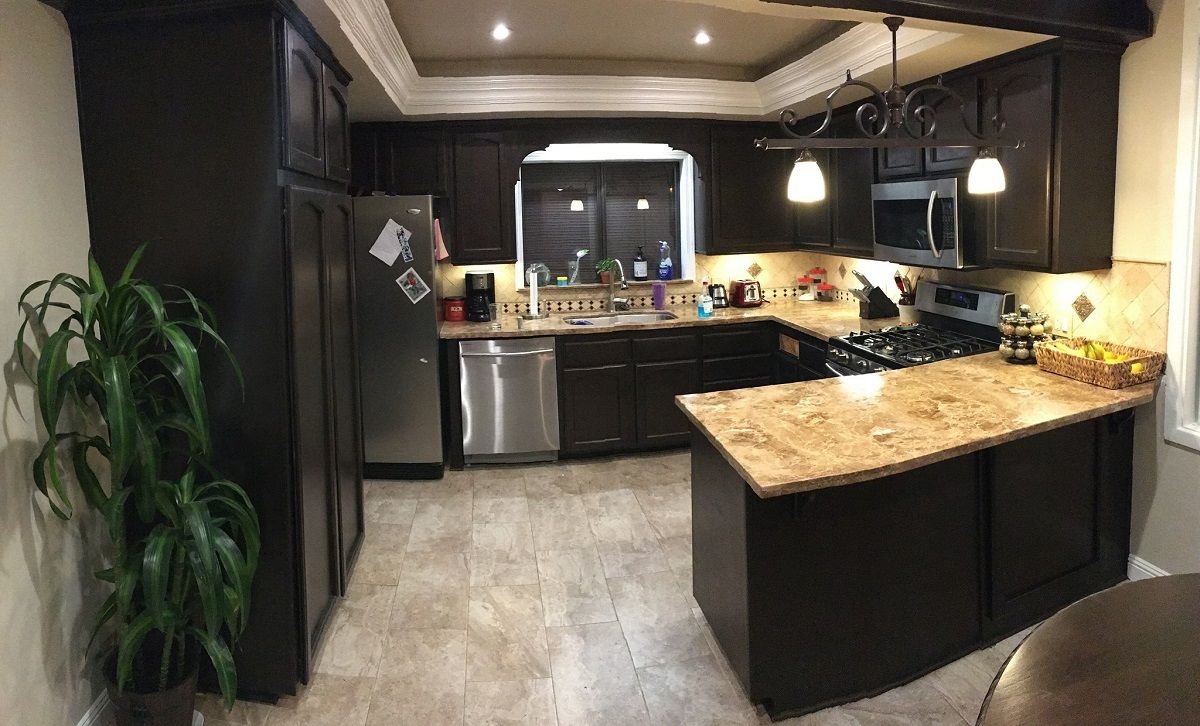 enlarged photo of modern kitchen with dark painted cabinets and beige marble counter tops
