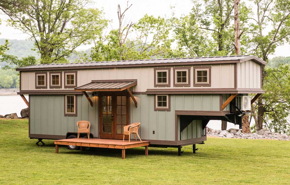 Timbercraft Tiny Homes' Retreat gooseneck tiny house; exterior photo showing the blue-gray cladding and covered porch area with double doors Timbercraft Tiny Homes' Retreat gooseneck tiny house; exterior photo showing the blue-gray cladding and covered porch area with double doors