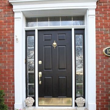 newly painted dark ebony door surround by windows with white framing in a brick house