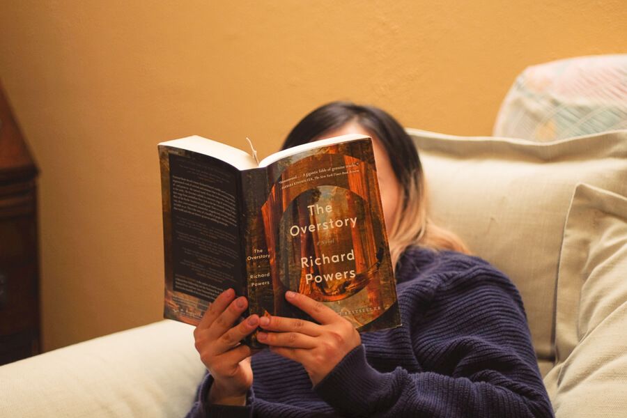 My friend reading a book held up to her face.