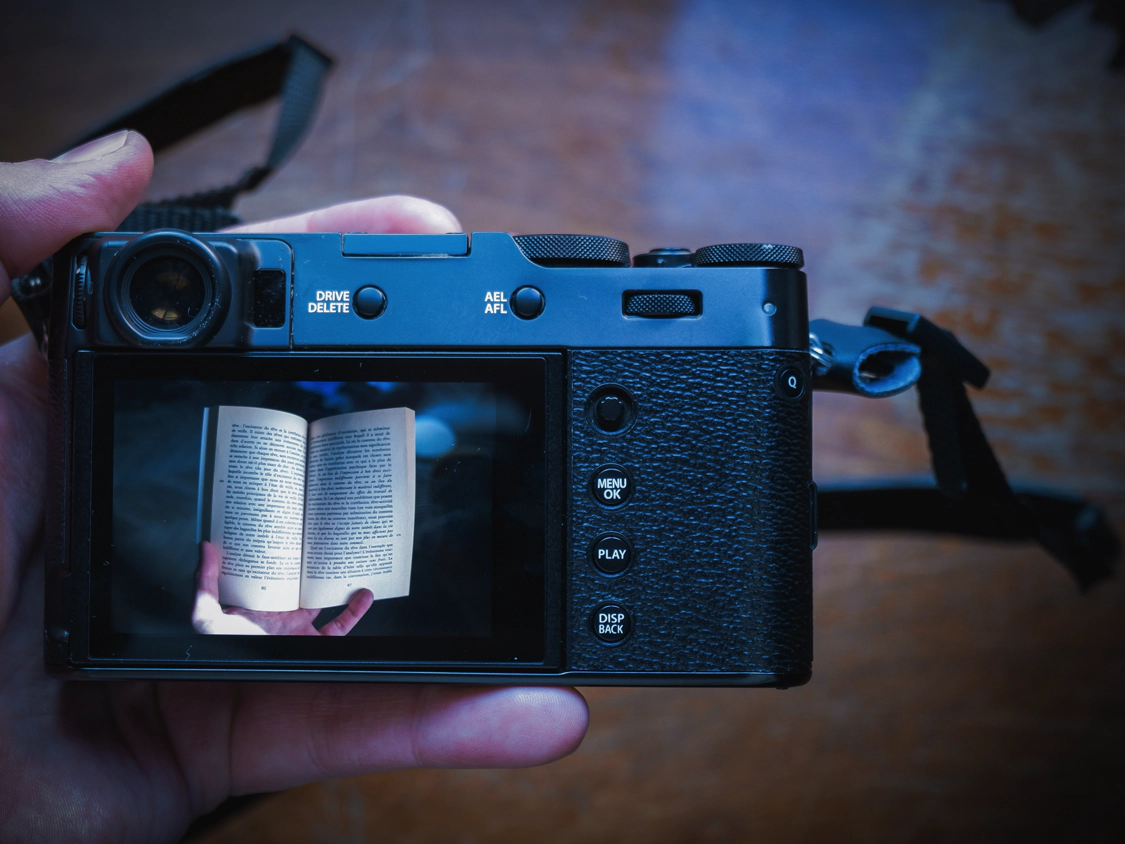 The FujiFilm X100V again. A photograph of a book is seen on the LCD screen.