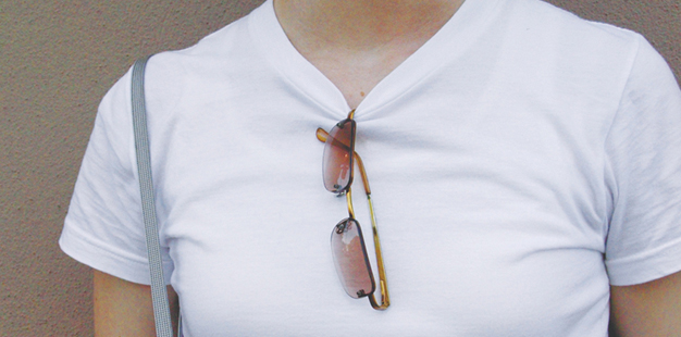 a woman has hung her sunglasses on the collar of her shirt.