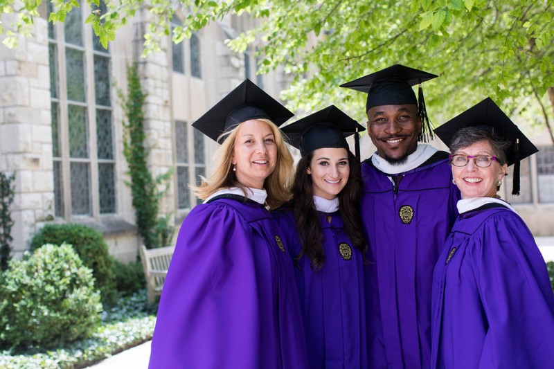 Northwestern University graduates smile for a group photo in their cap and gowns