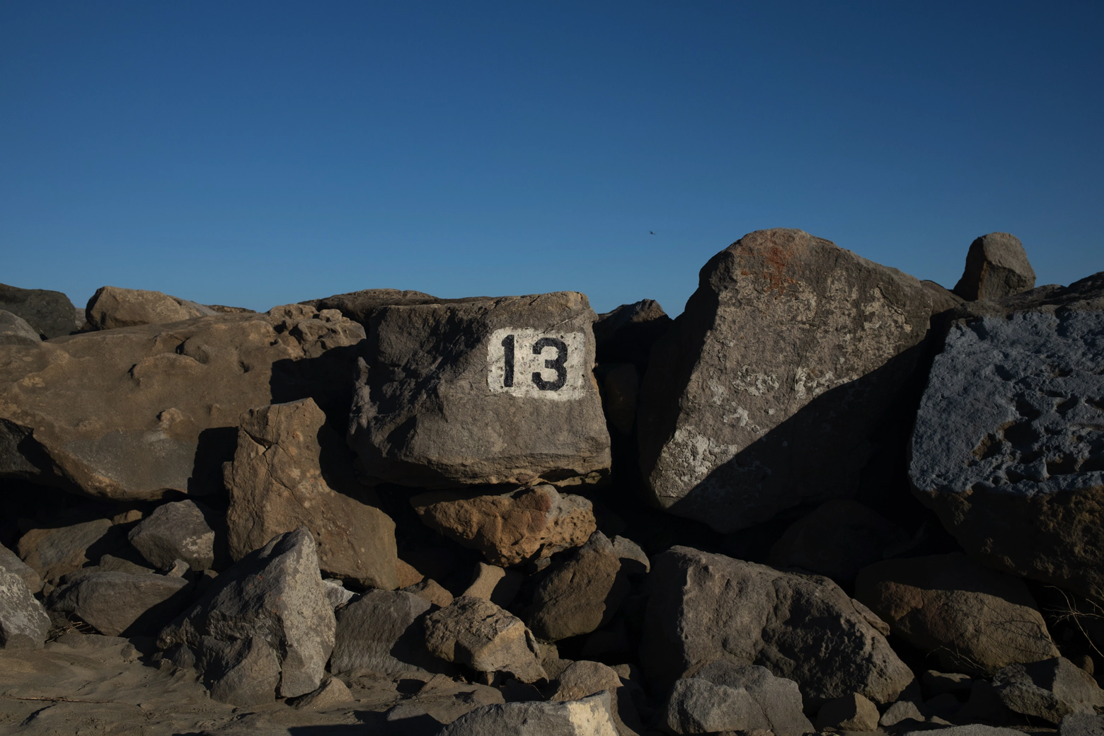 Large rocks along a shoreline with the number 13 painted on the center most rock