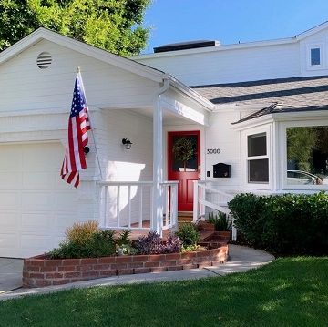 beautiful white painted home with green grass and a flying american flag