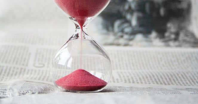 Zeitersparnis durch Prozessoptimierung Eine rote Sanduhr auf einer Zeitung