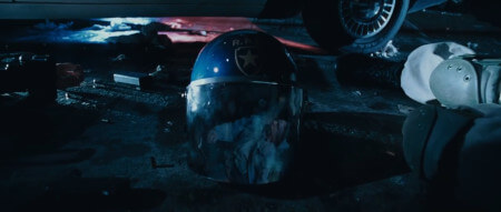 A close up of a discarded police riot helmet, showing the reflection of an approaching zombie hoard