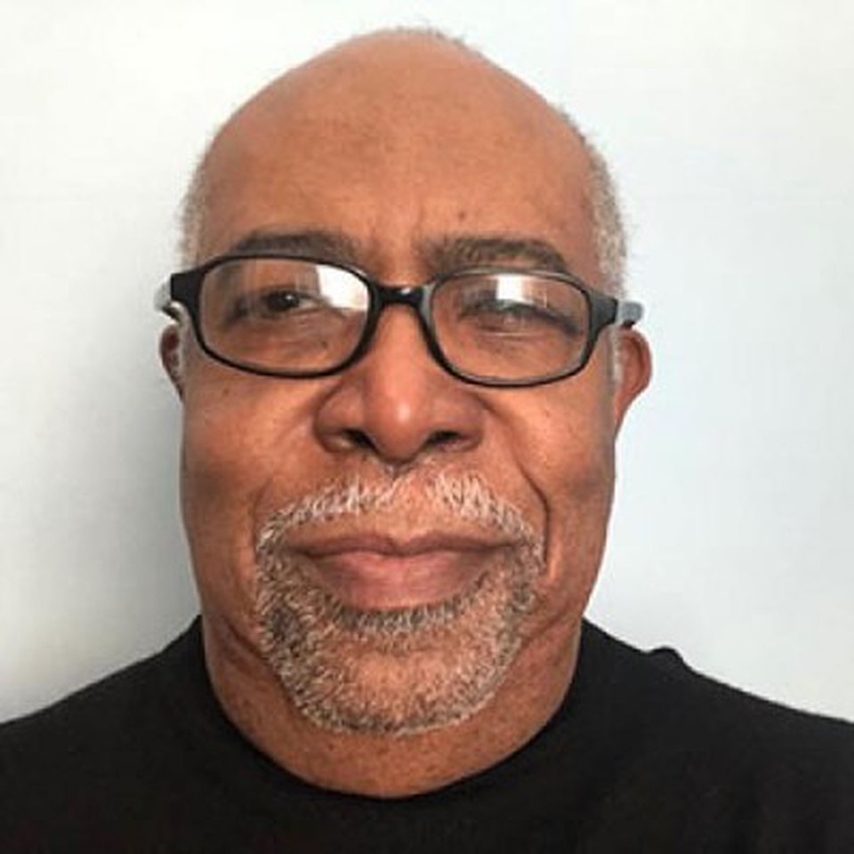 Professor Reginald Parquet - smiling and wearing a black cardigan