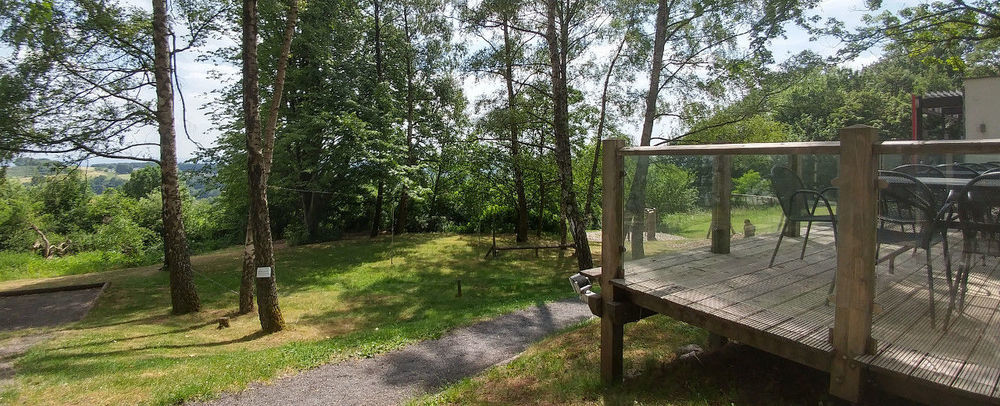 A photo taking outside of the venue in Rückersbach, showing parts of a terrace, some green and trees and a path through that.