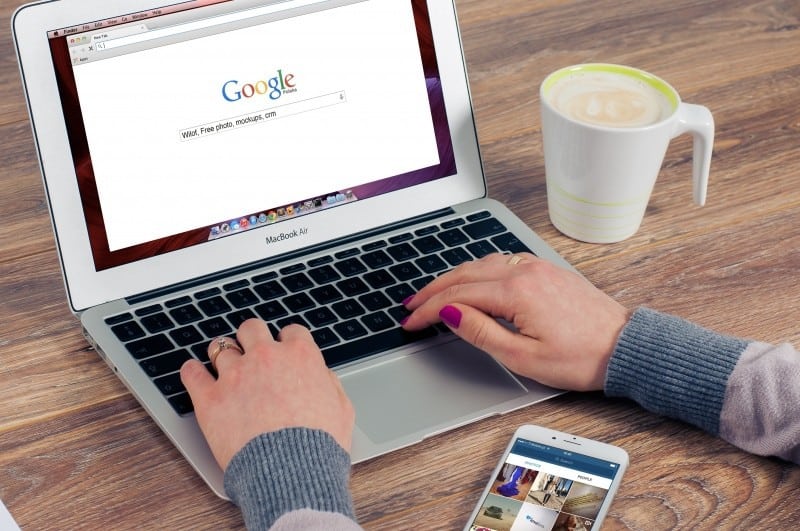 woman working on laptop with mobile phone and coffee cup on table