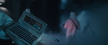 A person in a hazmat suit shows the viewer a device which looks a lot like a motion tracker from Aliens
