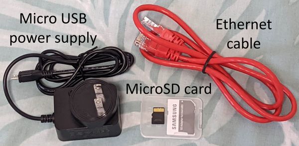 A black micro USB power supply, red ethernet cable, and small black microSD storage card.