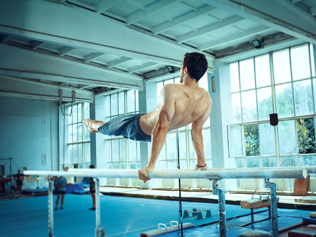 A gymnast doing a routine on the parallel bars inside of a gym
