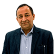 Portrait of a South Asian man in a pinstriped suit jacket looking into the camera with a slight smile.
