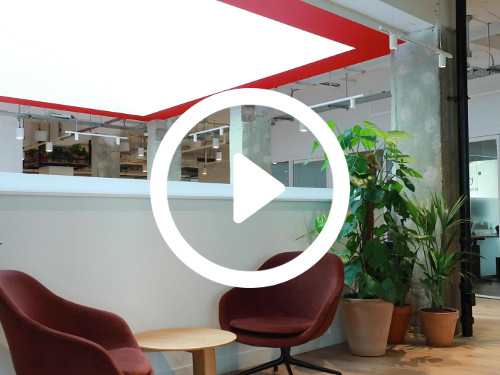 Open workspace featuring artistic ceiling design above two brown egg chairs with small round wooden table next to plants Google Meet background