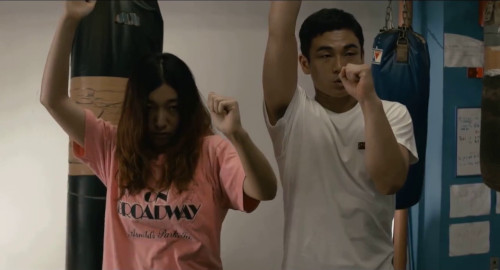  A screenshot from the movie '100 Yen Love' of Ichiko timidly mimicking the boxing stance of her trainer.