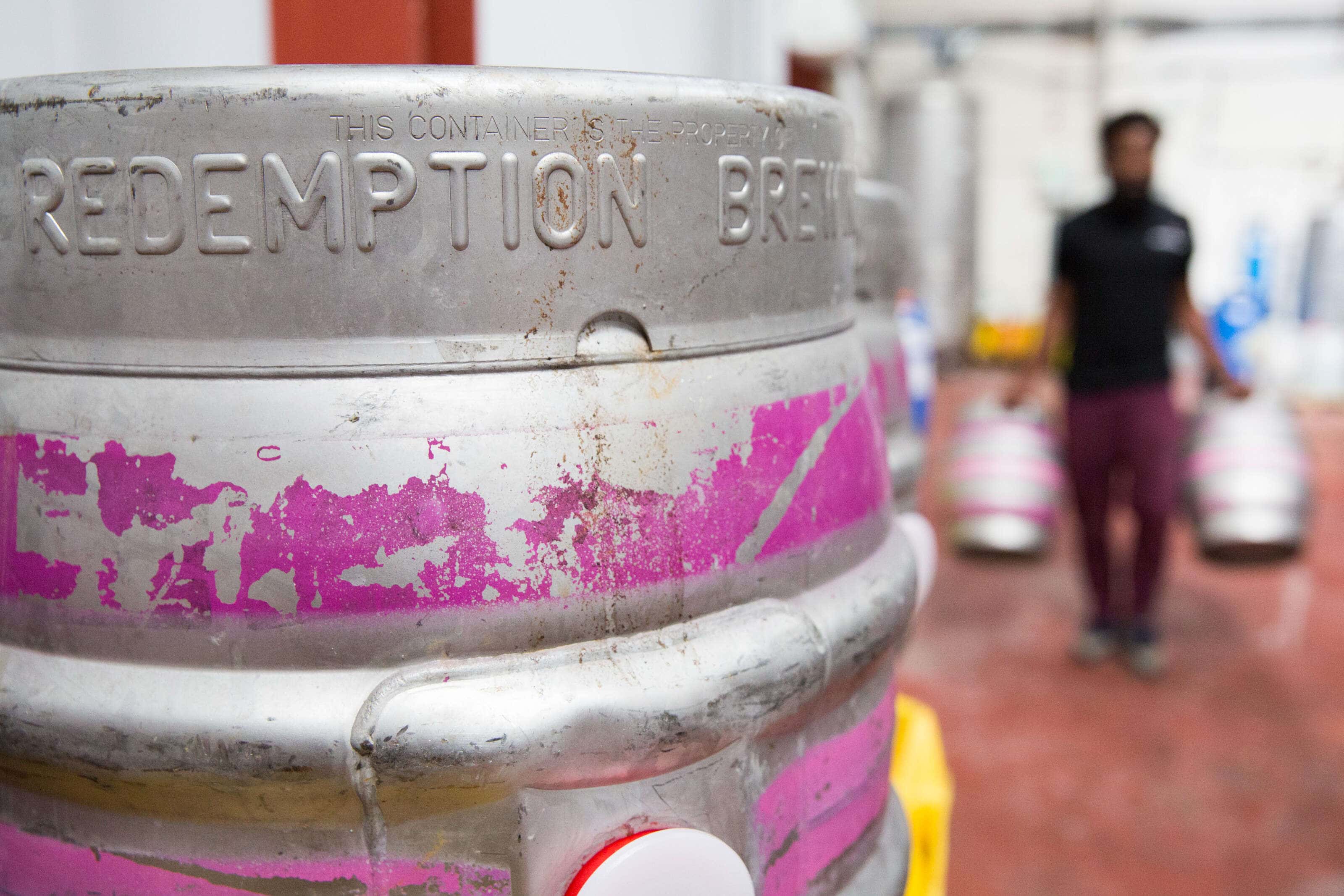 Redemption Brewery cask with a person carryinng two casks in the backgroun