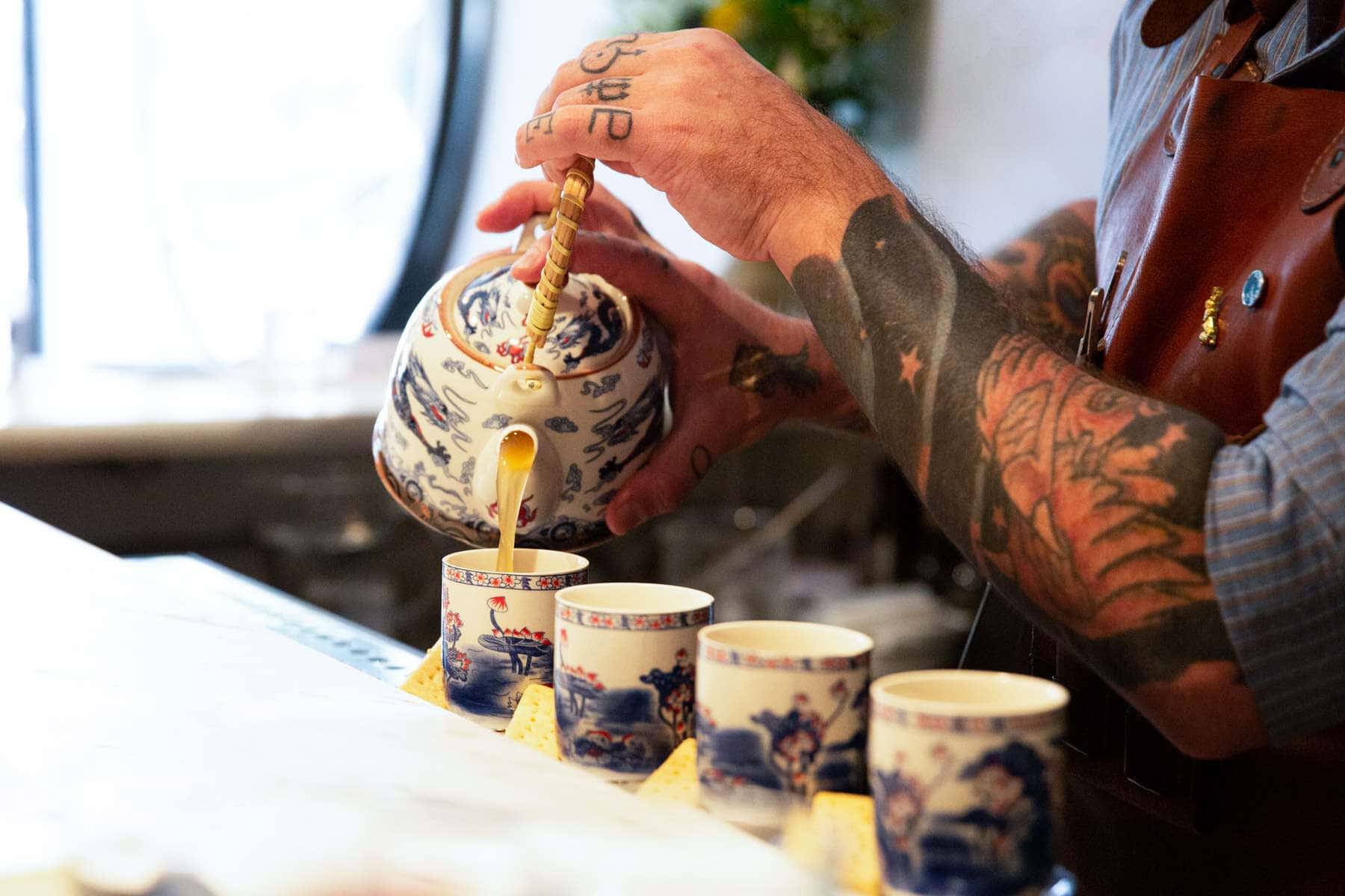 tea-cocktail-being-pored-by-tattooed-bartender