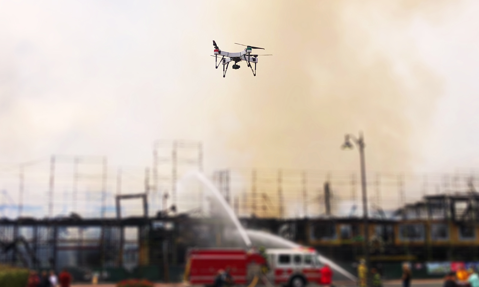 Drone flying in front of firefighters extinguishing a building fire