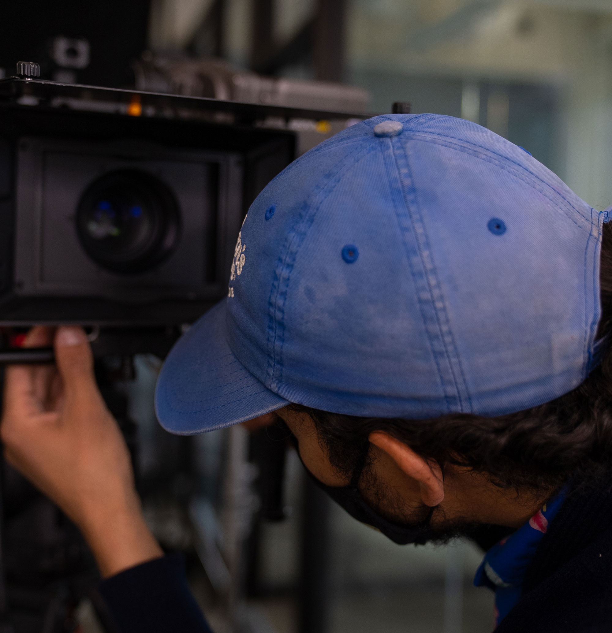 A close-up of a man wearing a hat setting up a video camera