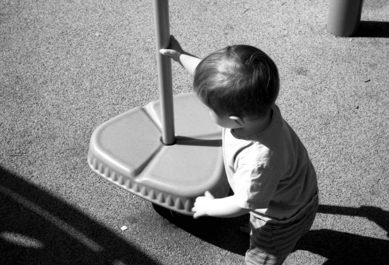 A baby playing with a balancing pole on the playground