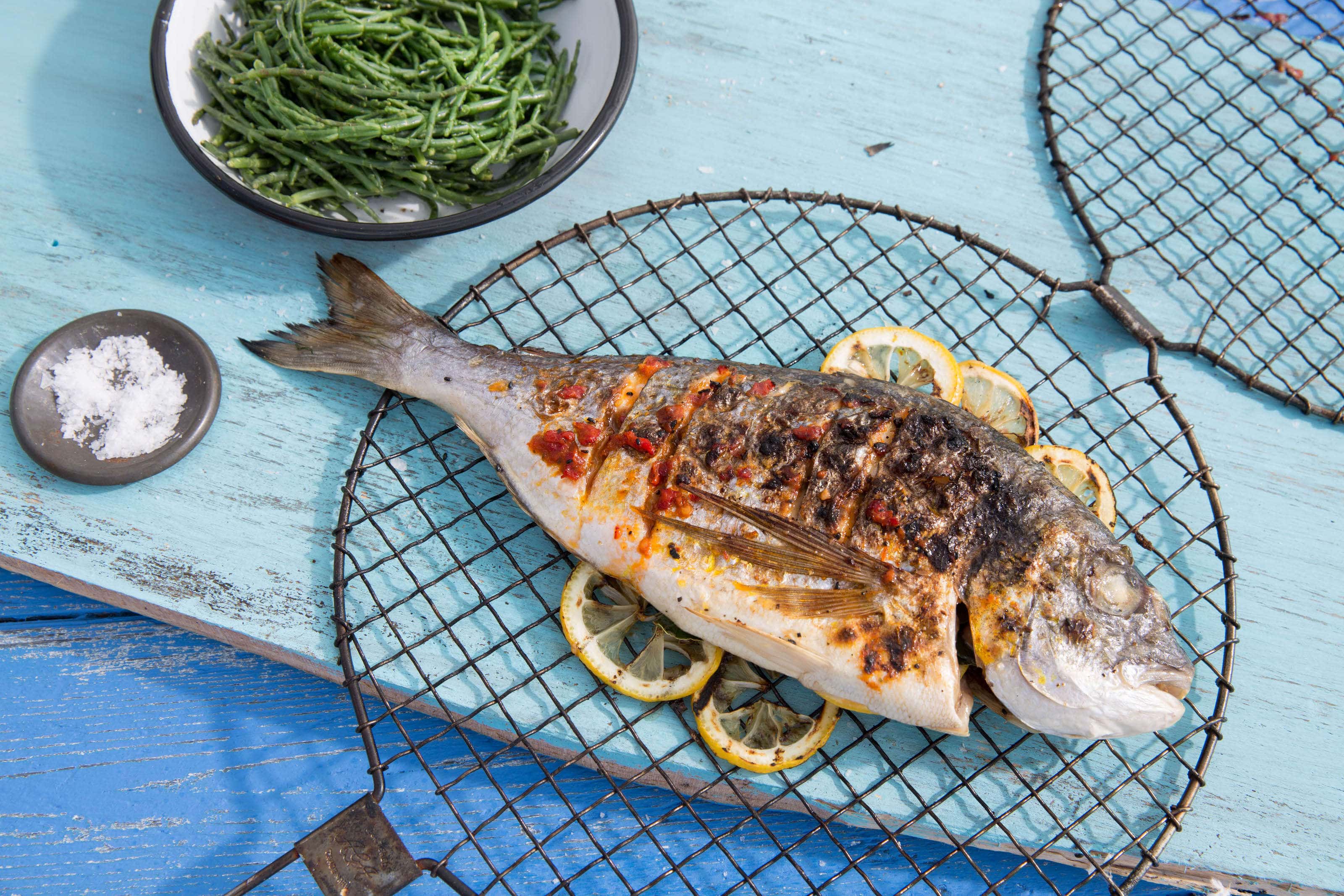 Cooked Sea bream on a turquoise table with salt and samphire.