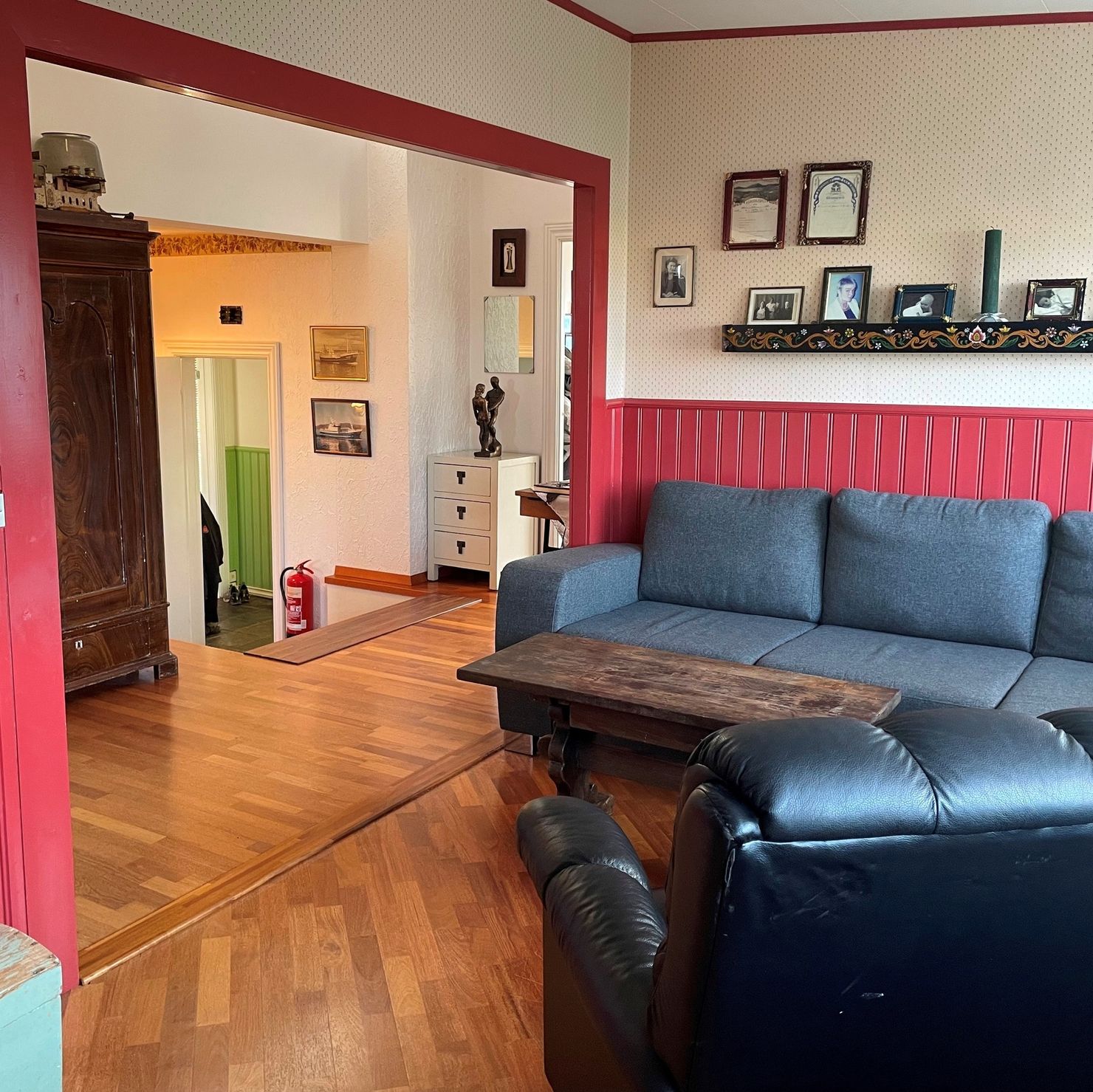The living area has pretty red-painted, half-height wood panelling and a cosy couch
