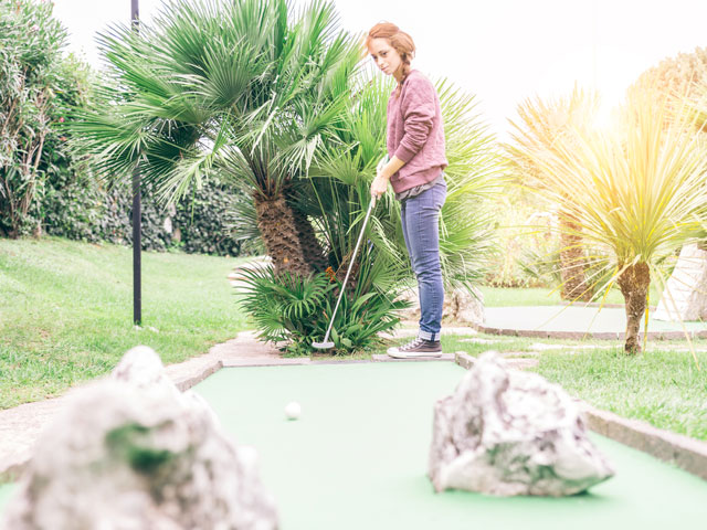 A woman hitting a ball between two rocks on the green