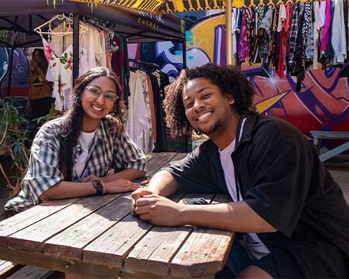 Two attendees smiling while sitting at a bench