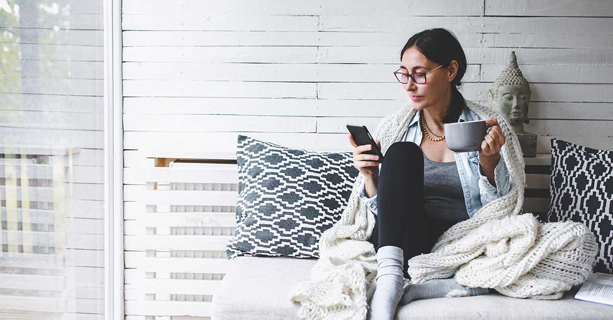A woman holding a coffee cup in one hand, using her phone with the other. Learn how 2020 has changed online user behavior.