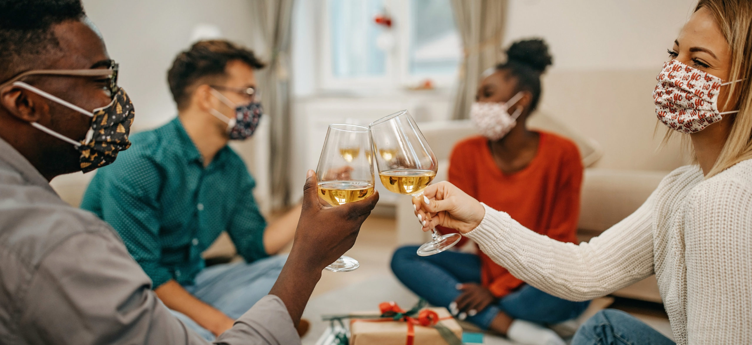 Four young people sharing glasses of wine and exchanging gifts