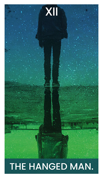 The Hanged Man card. A man and his reflection stand on a path.