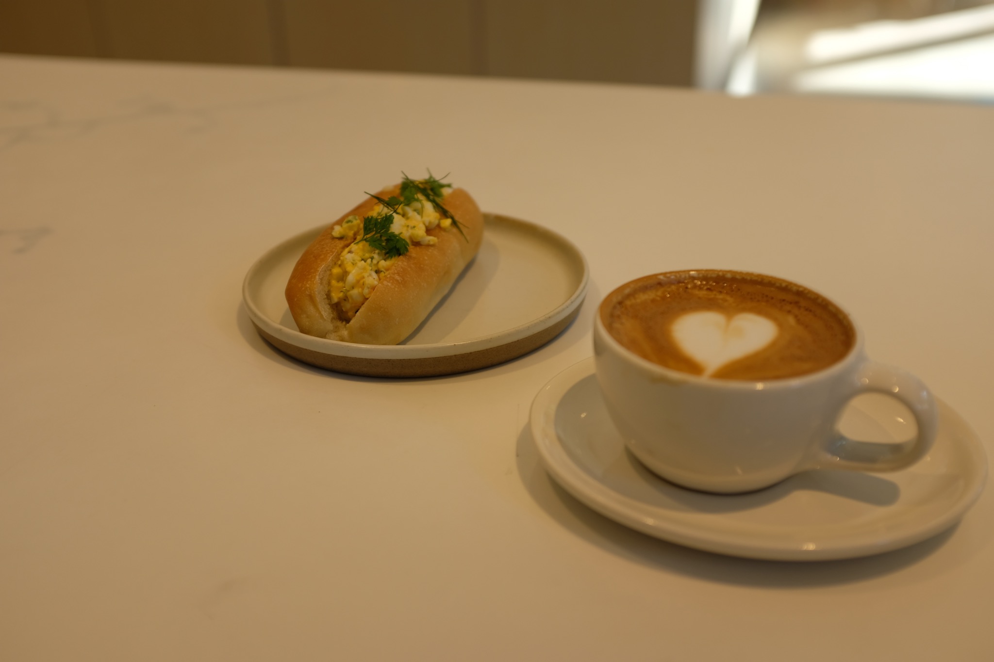 An egg sandwich (cold) served with a cappuccino
