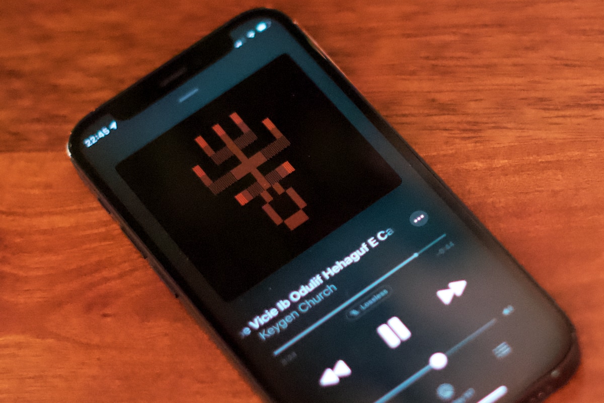 A phone with the music app front and center. The album cover is an abstract, symmetrical shape in ANSI art form.