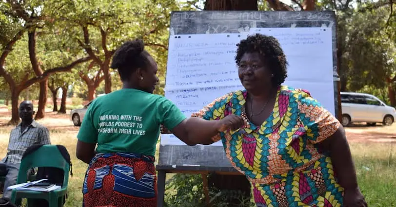 Two Malawian women demonstrating a COVID-19 greeting at an information session.
