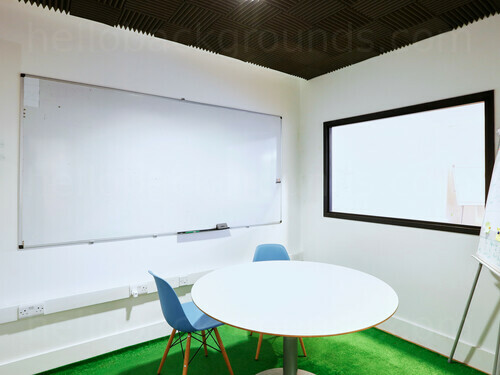 Basic white walled meeting room with city views containing whiteboard next white circular table and blue chairs   Zoom background