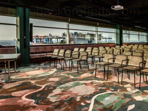 Large artistic style conference room with city views and cream coloured audience seating Skype background