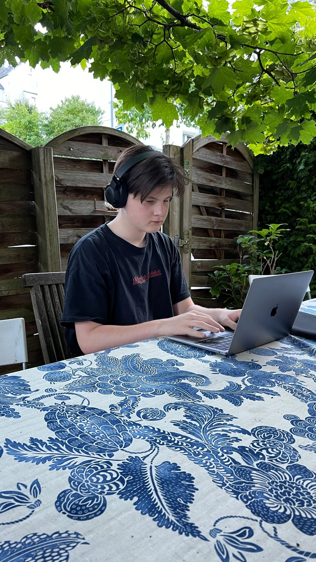 Oli sitzt im Garten und töggelet auf seinem Laptop.