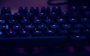 focus photography of computer keyboard with purple lights