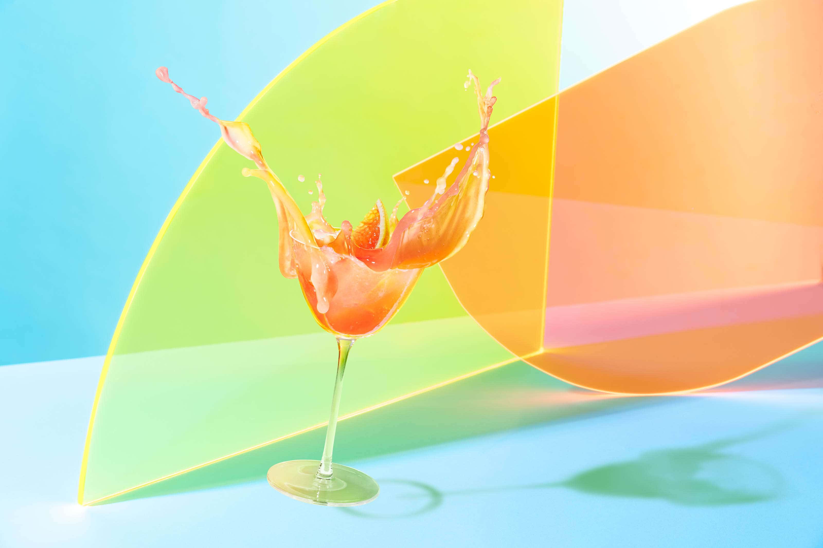 cocktail splashing out of glass with colourful background