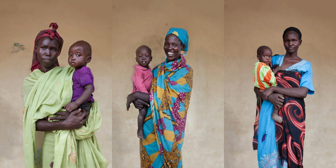 Three South Sudanese women with their infants outside of a maternal health clinic in rural South Sudan