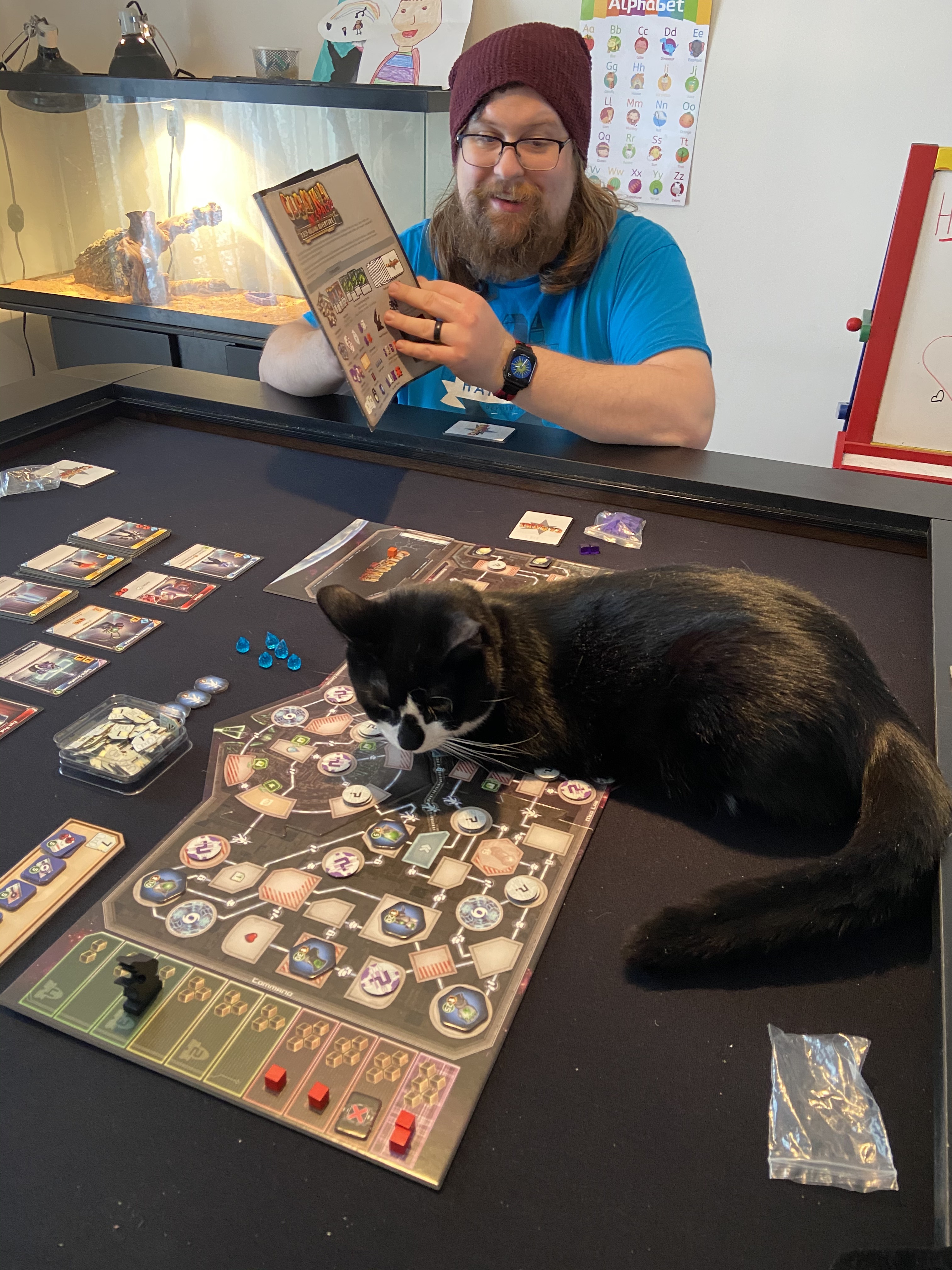 Photograph of Aaron with his cat playing board games