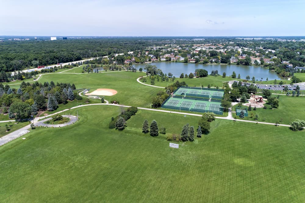 Aerial view of a suburban park district area with a soccer field, tennis courts, lake and playground in Lake County, IL. USA