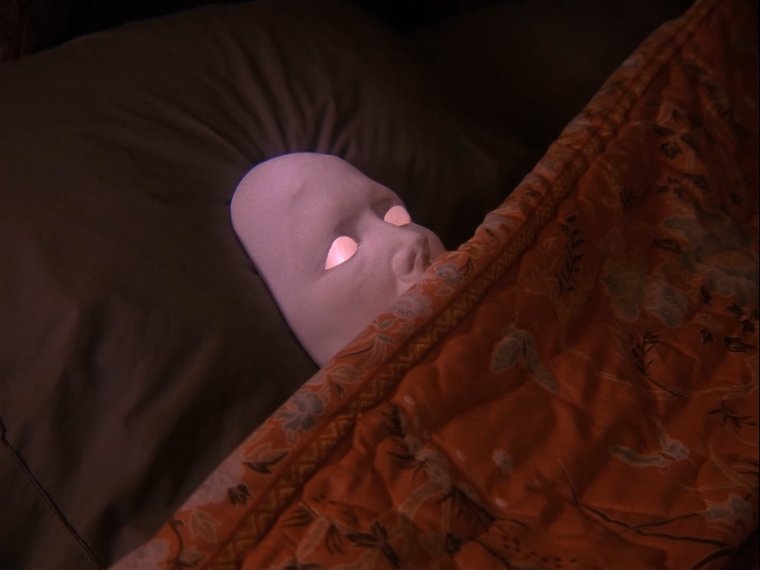 creepy mask on the bed under the blanket
