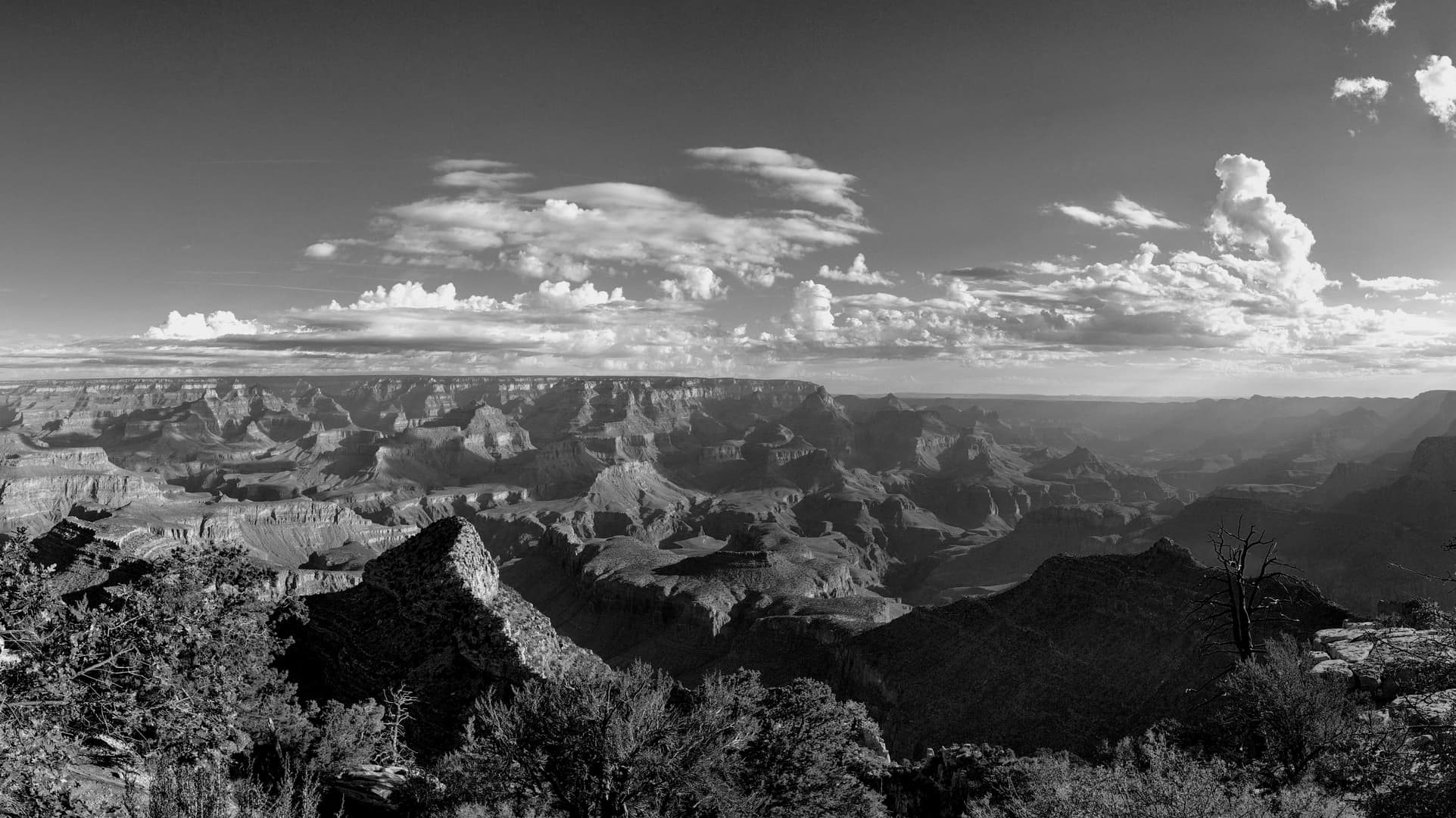 A black-and-white photograph of the Grand Canyon shortly after dawn.